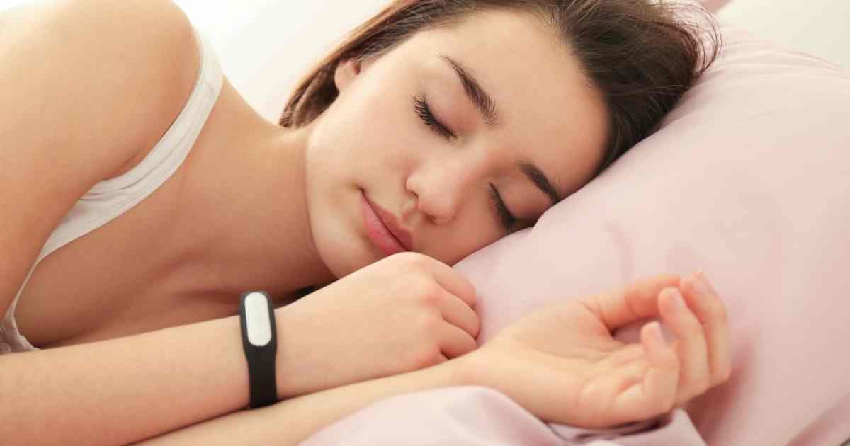 woman sleeping with sleep tracker on wrist
