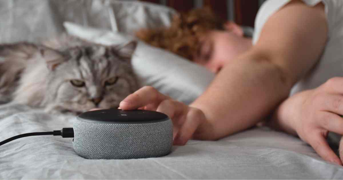 man in bed adjusts white noise machine